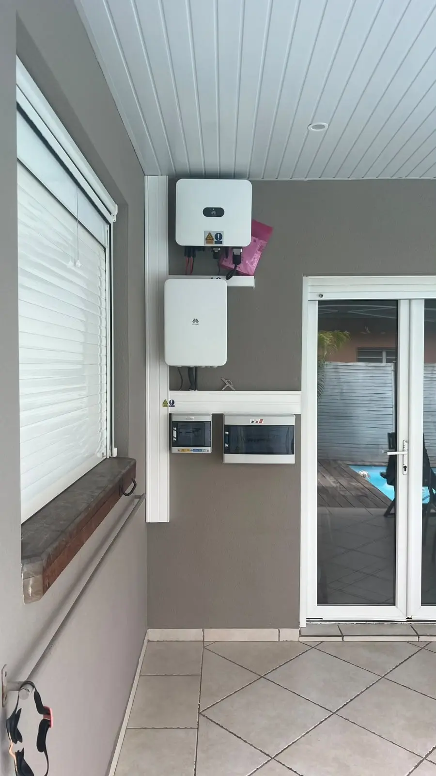 Onduleur Huawei et coffrets de protection électrique posés sous goulottes sur le mur d’une terrasse