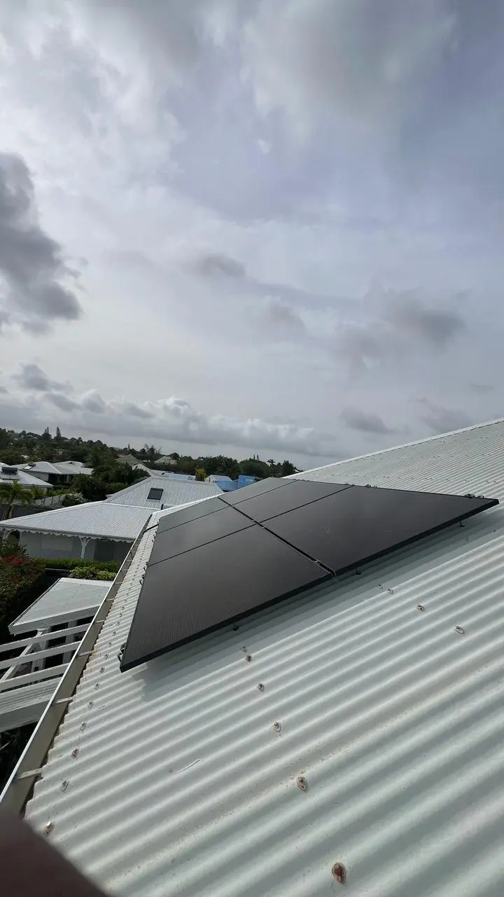Quatre panneaux photovoltaïques sur une toiture en tôle dans un quartier résidentiel